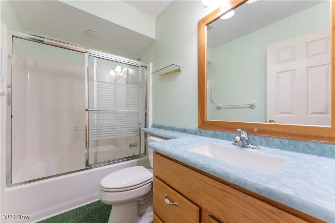 Bathroom featuring bath / shower combo with glass door and vanity