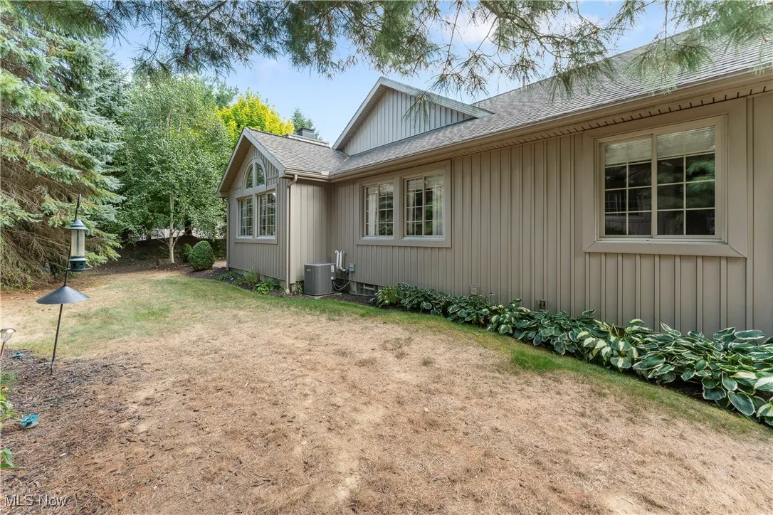 Back of property featuring roof with shingles, a lawn, and board and batten siding