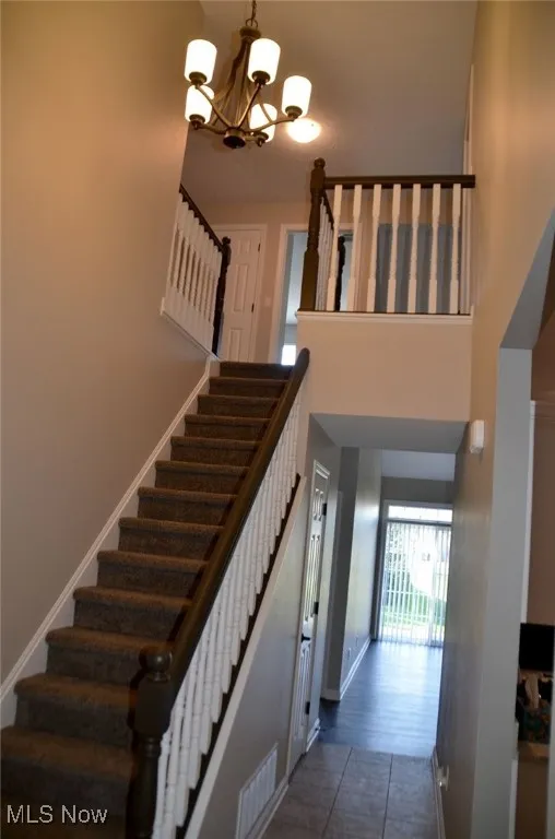 Impressive Staircase to the second floor with a chandelier and a high ceiling