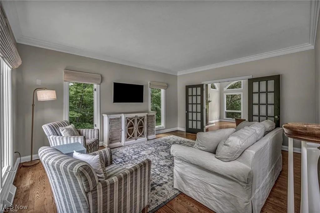 Living area featuring ornamental molding, plenty of natural light, and wood finished floors
