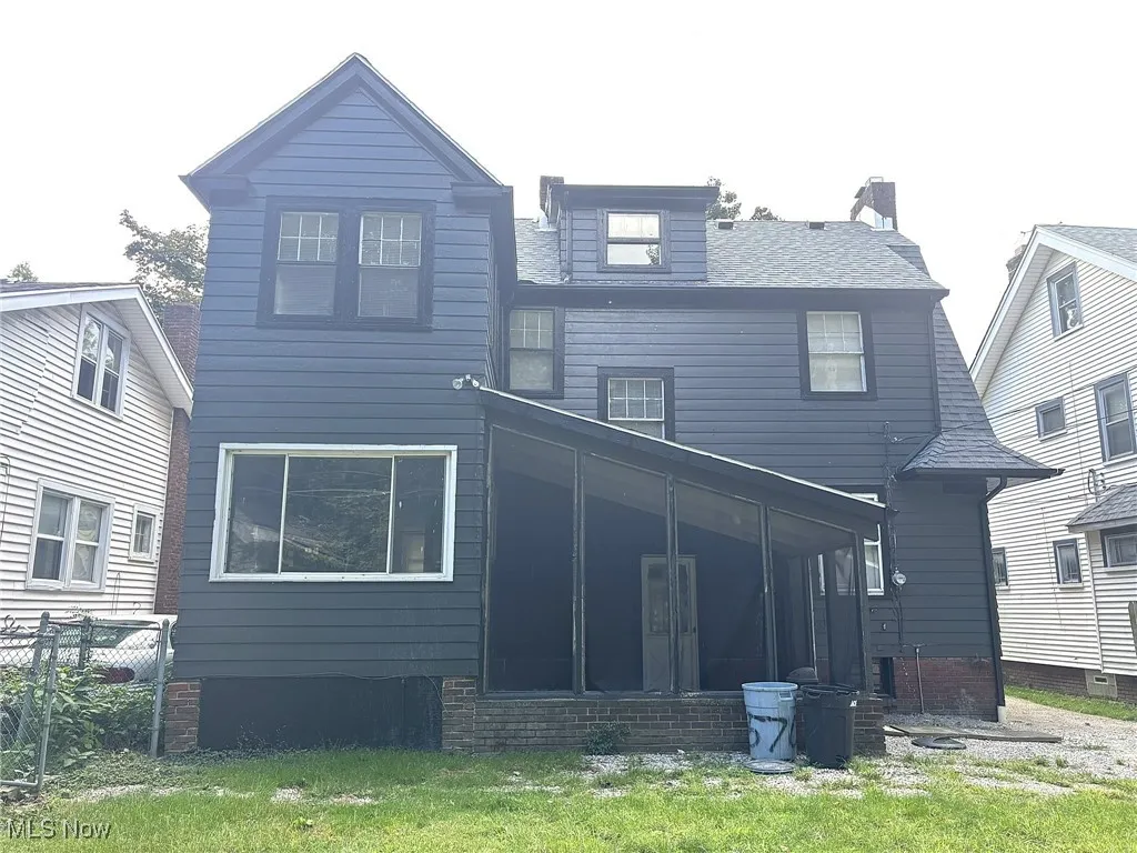 Back of house featuring a sunroom, a lawn, a shingled roof, and a chimney