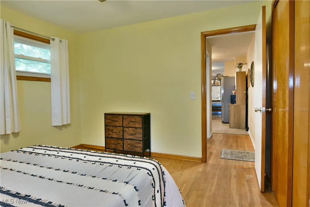 Bedroom with light wood-type flooring and freestanding refrigerator