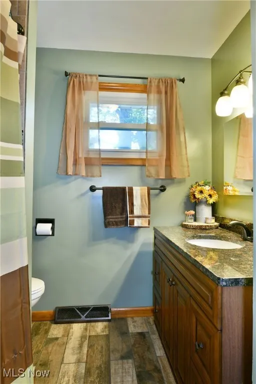 Bathroom with vanity, dark wood finished floors, and a shower with shower curtain