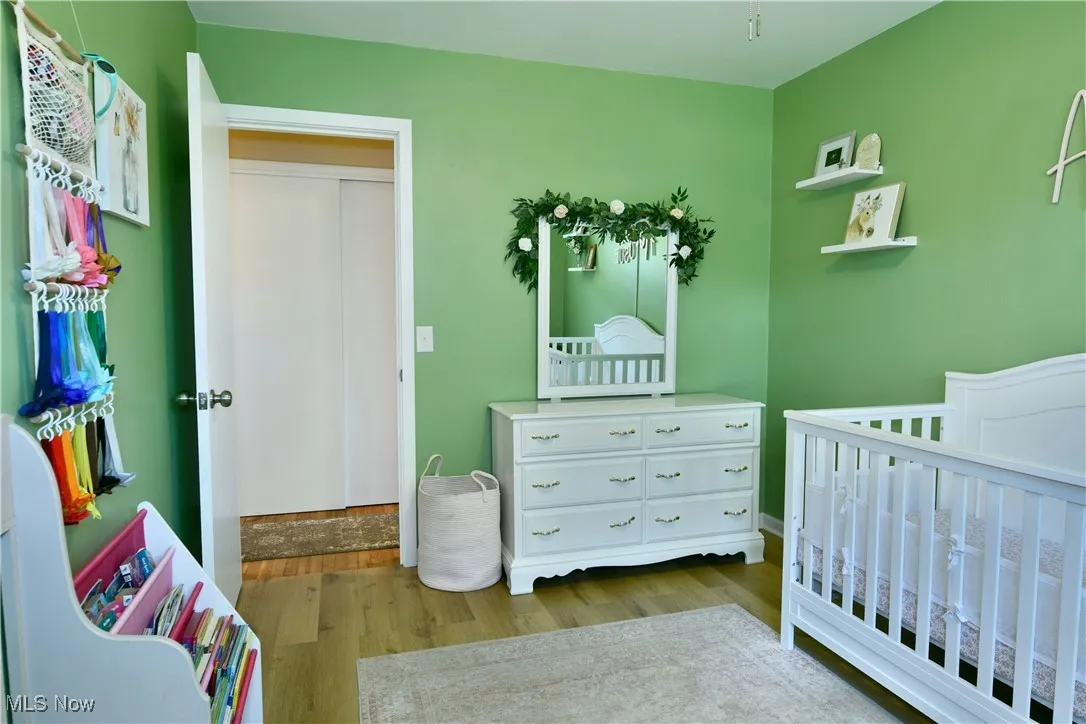 Bedroom featuring light wood-type flooring and a crib