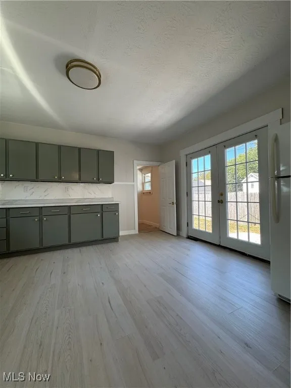 Kitchen featuring light wood-style flooring, light countertops, fridge, french doors, and a textured ceiling