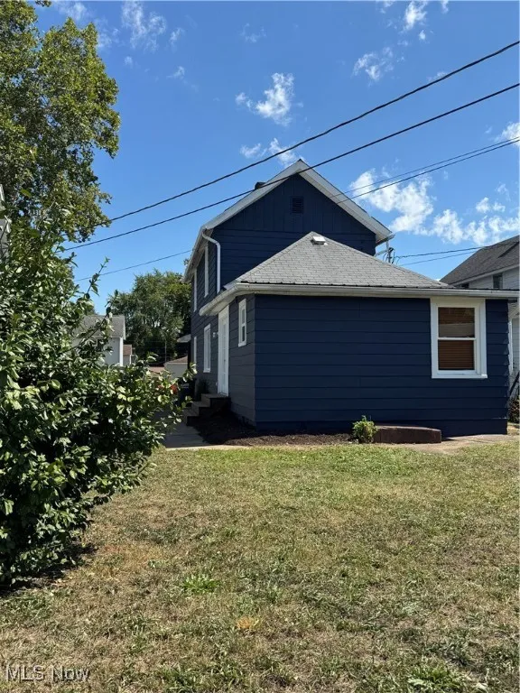 View of side of home featuring a lawn, a shingled roof, and board and batten siding