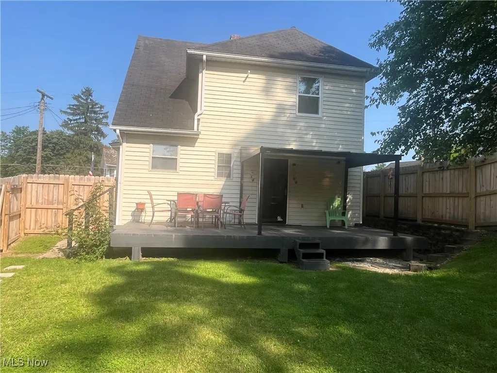 Rear view of house featuring a deck, a fenced backyard, and roof with shingles