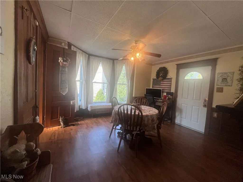 Dining space featuring wood finished floors, a drop ceiling, and a ceiling fan