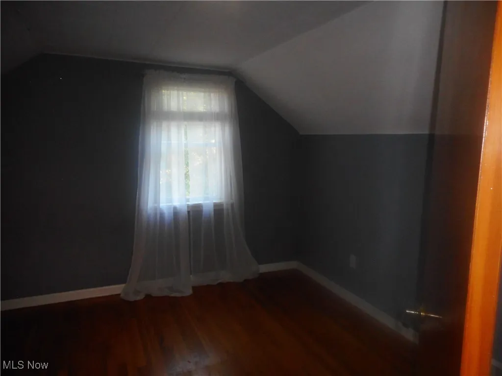 Additional living space with dark wood finished floors and lofted ceiling