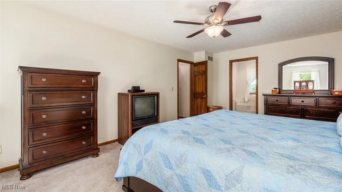 Bedroom with light carpet, a ceiling fan, and a textured ceiling