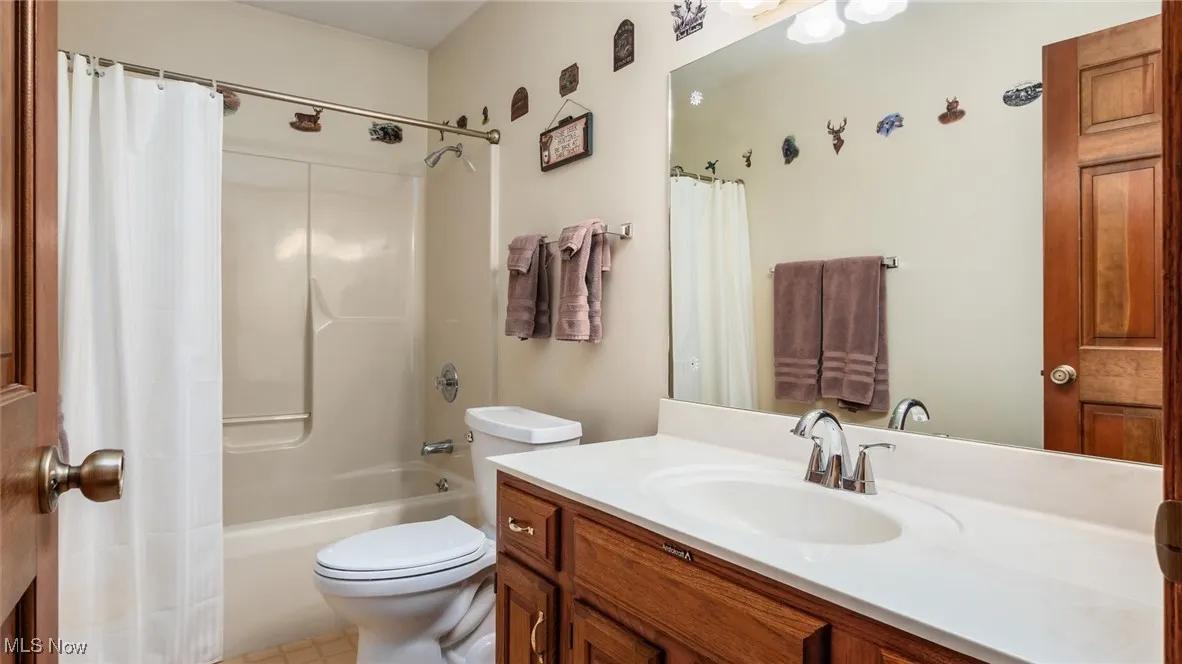 Bathroom featuring vanity, shower / tub combo with curtain, and light tile patterned flooring