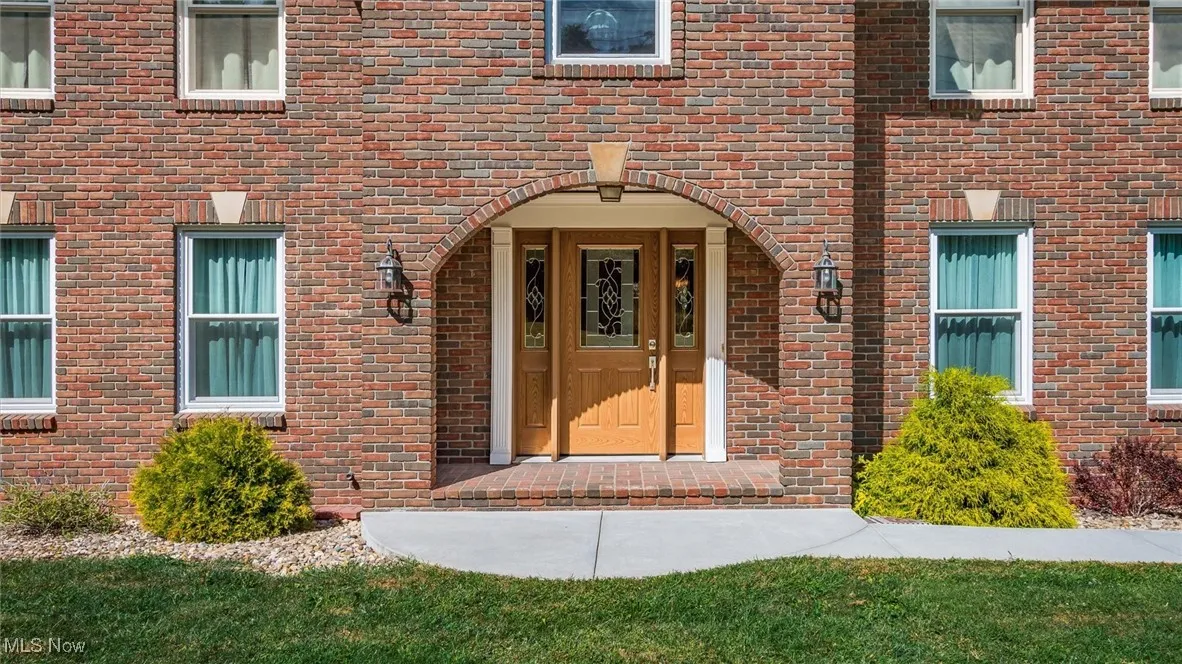 Entrance to property featuring brick siding and a lawn