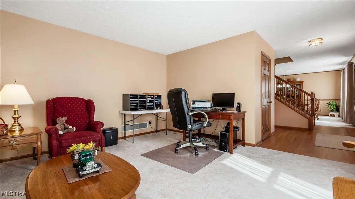 Carpeted office space featuring baseboards and wood finished floors