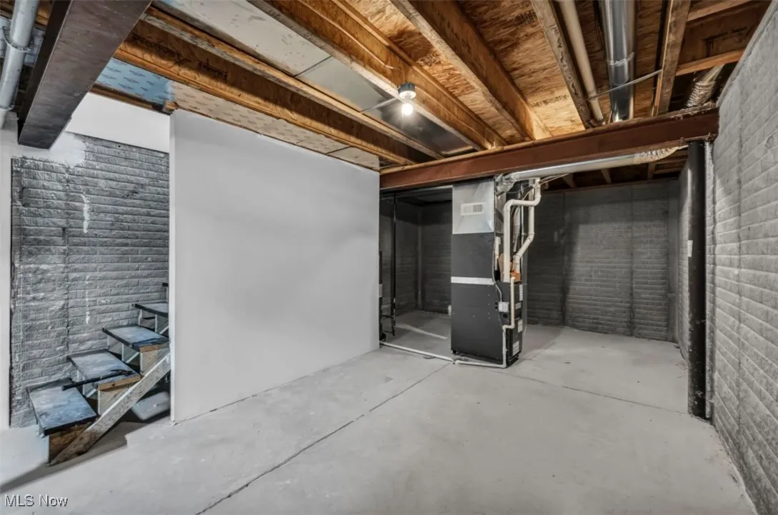 Unfinished basement featuring stairway and heating unit