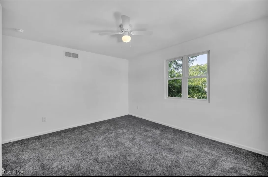 Spare room with dark carpet and ceiling fan