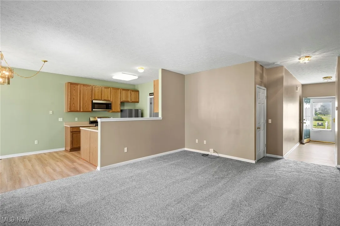 Kitchen featuring brown cabinetry, light carpet, a textured ceiling, light countertops, and a chandelier