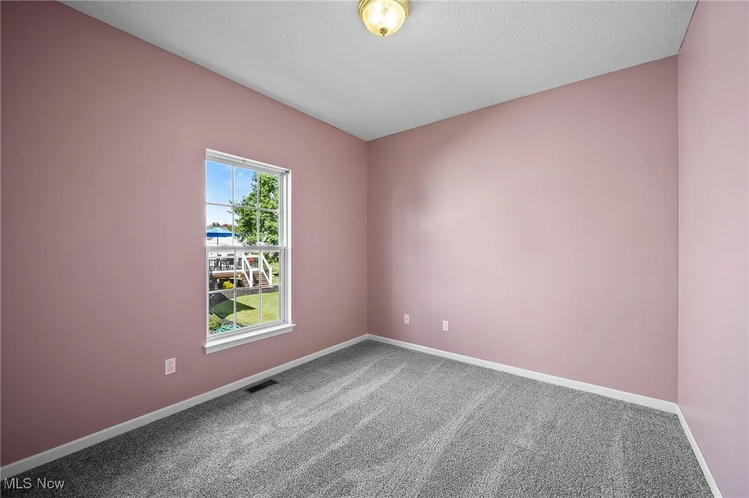 Carpeted spare room featuring baseboards and a textured ceiling