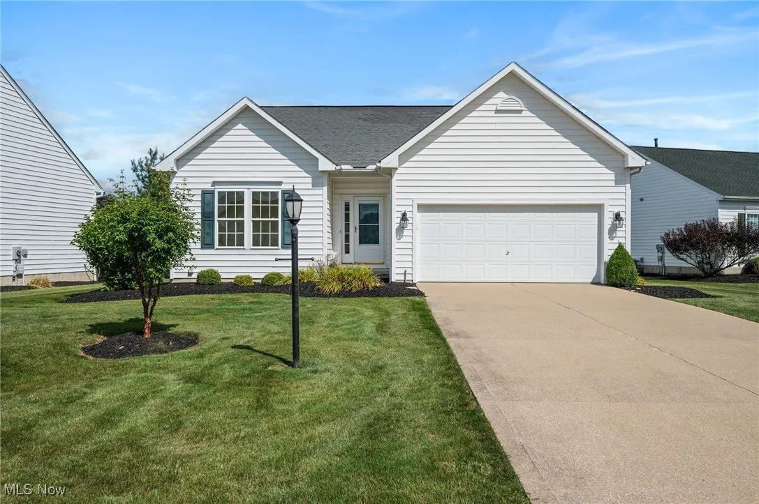 Ranch-style home with driveway, a front yard, a shingled roof, and an attached garage