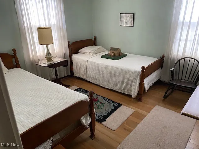 Bedroom with wood finished floors and multiple windows
