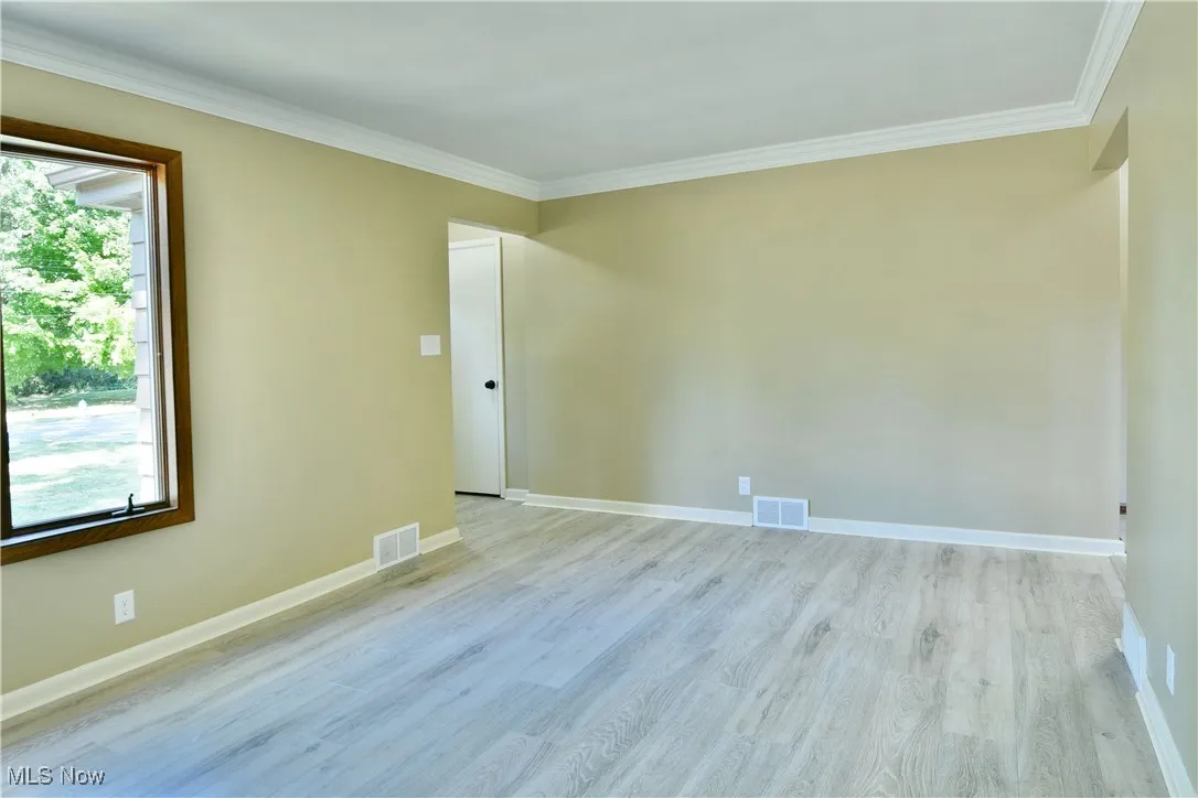Unfurnished room featuring ornamental molding and wood finished floors