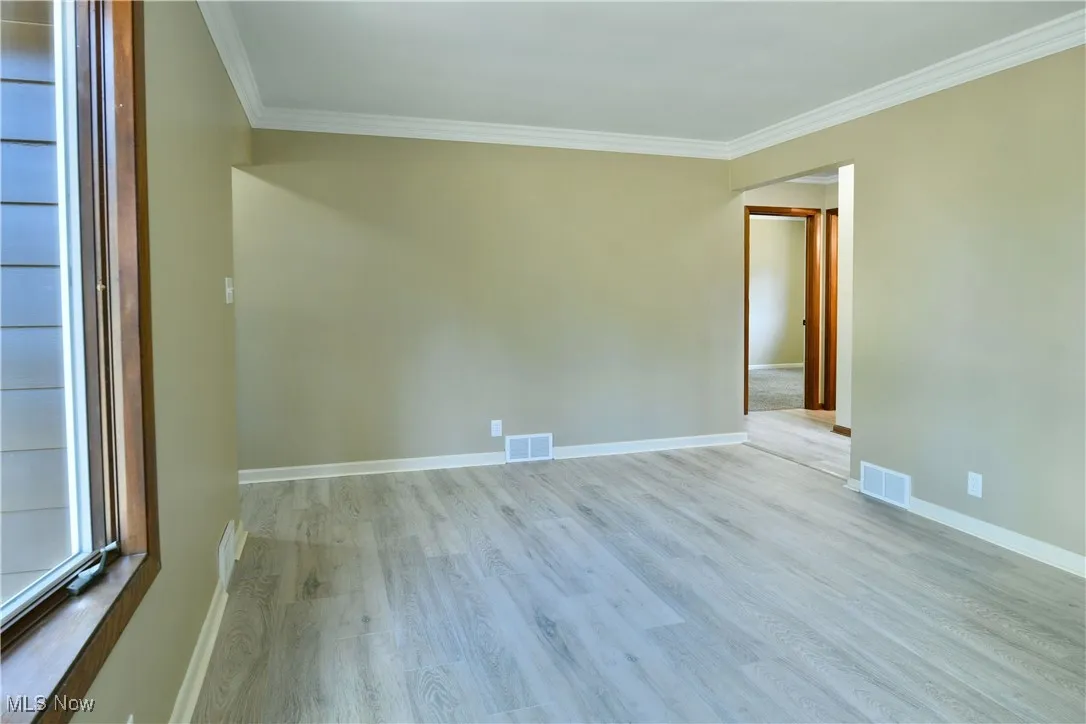 Spare room featuring ornamental molding and light wood-type flooring