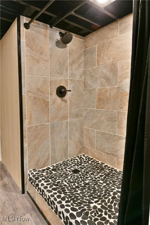 Full bath featuring a shower stall and wood finished floors