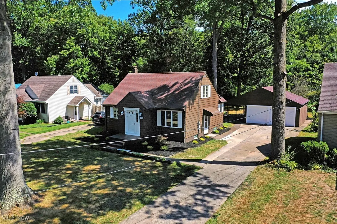View of front of home with an outbuilding, a detached garage, and roof with shingles