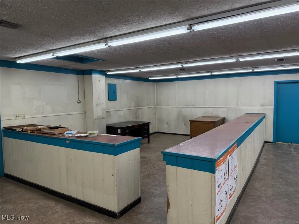 Miscellaneous room featuring concrete floors, a textured ceiling, electric panel, and visible vents