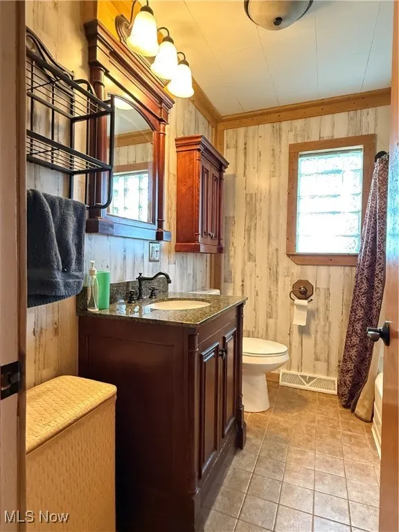 Bathroom with vanity, light tile patterned flooring, and wood walls