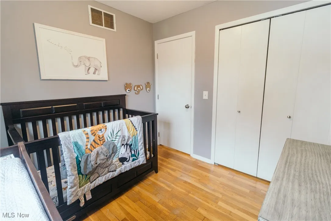 Bedroom featuring light wood finished floors, a nursery area, and a closet