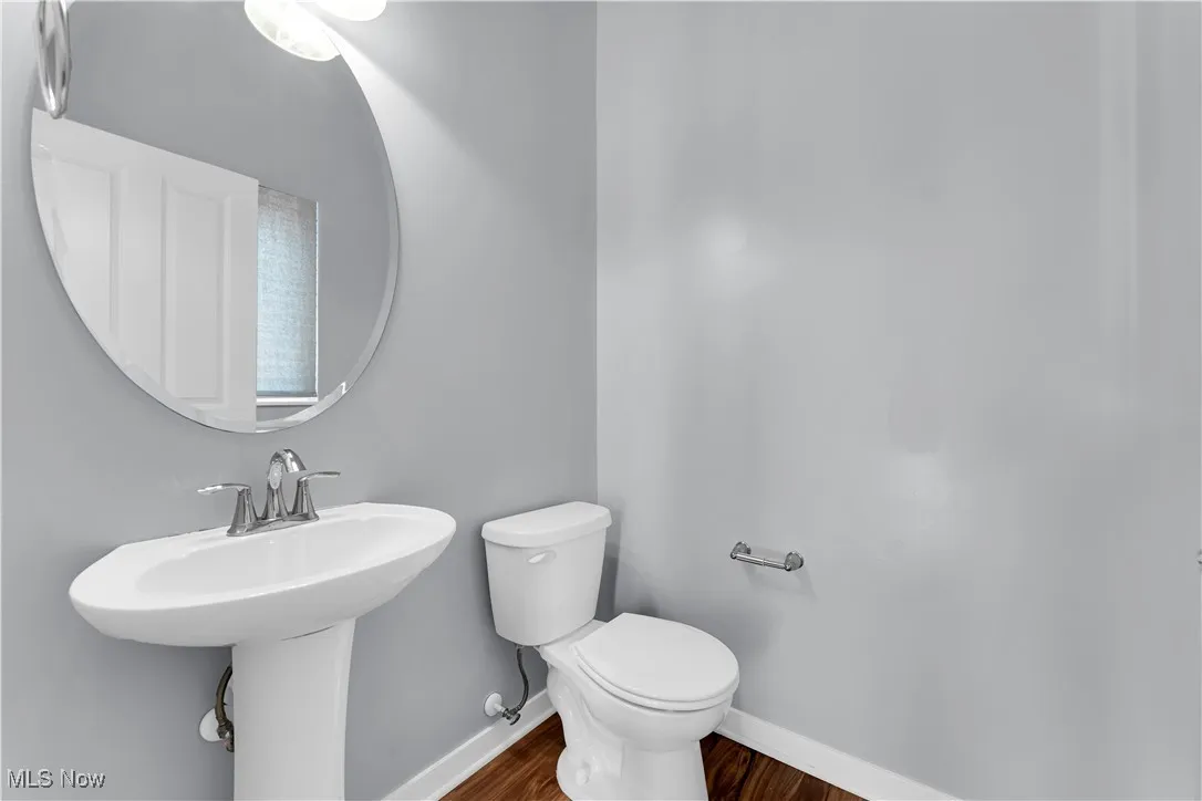Half bath featuring toilet and dark wood-style floors