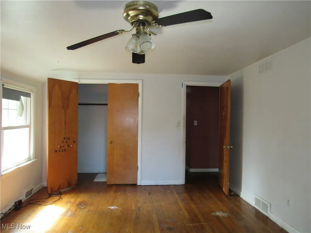 Unfurnished bedroom featuring hardwood / wood-style flooring, ceiling fan, and a closet