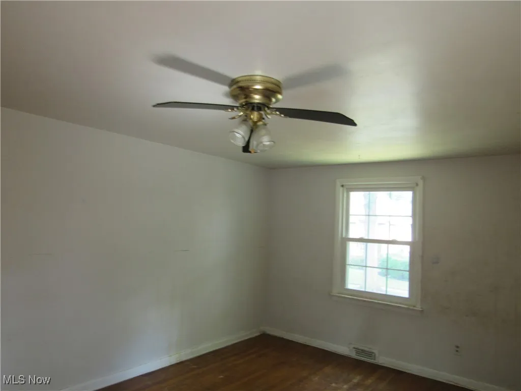 Spare room featuring dark wood finished floors and ceiling fan