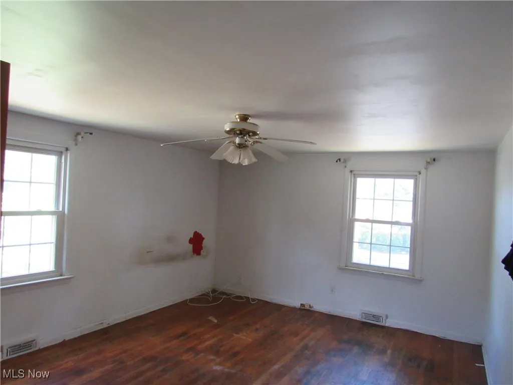 Empty room with dark wood-style flooring and a ceiling fan