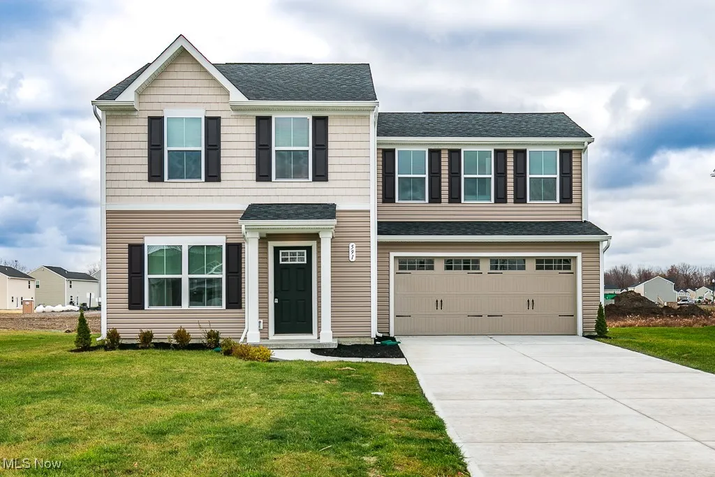 View of front facade with a shingled roof, an attached garage, driveway, and a front yard
