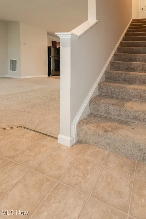 Stairway with carpet floors and tile patterned flooring