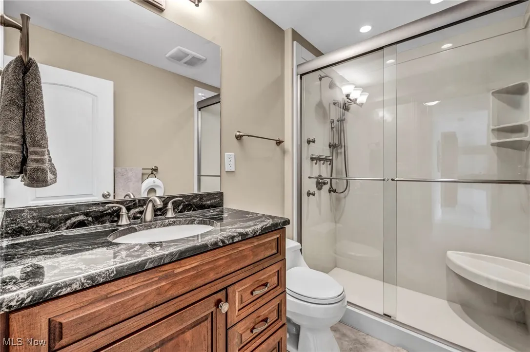 Bathroom with a shower stall, vanity, and recessed lighting