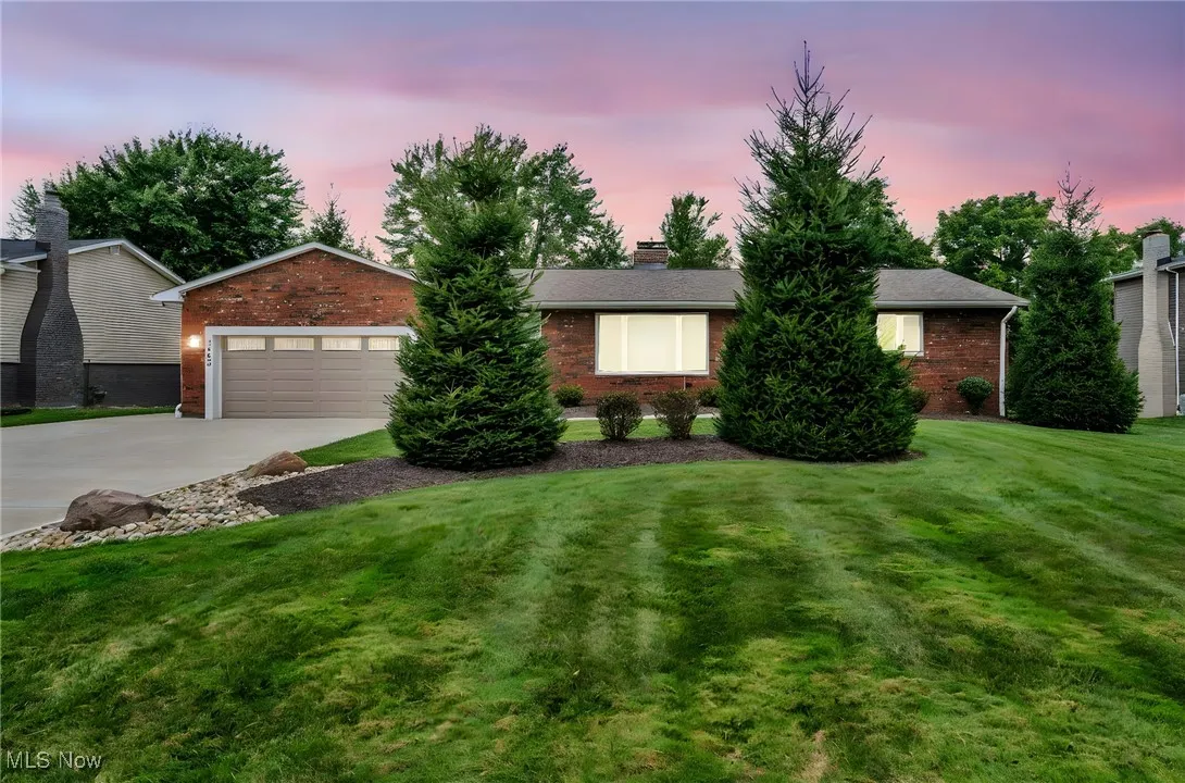 Single story home featuring a front yard, driveway, brick siding, and a garage