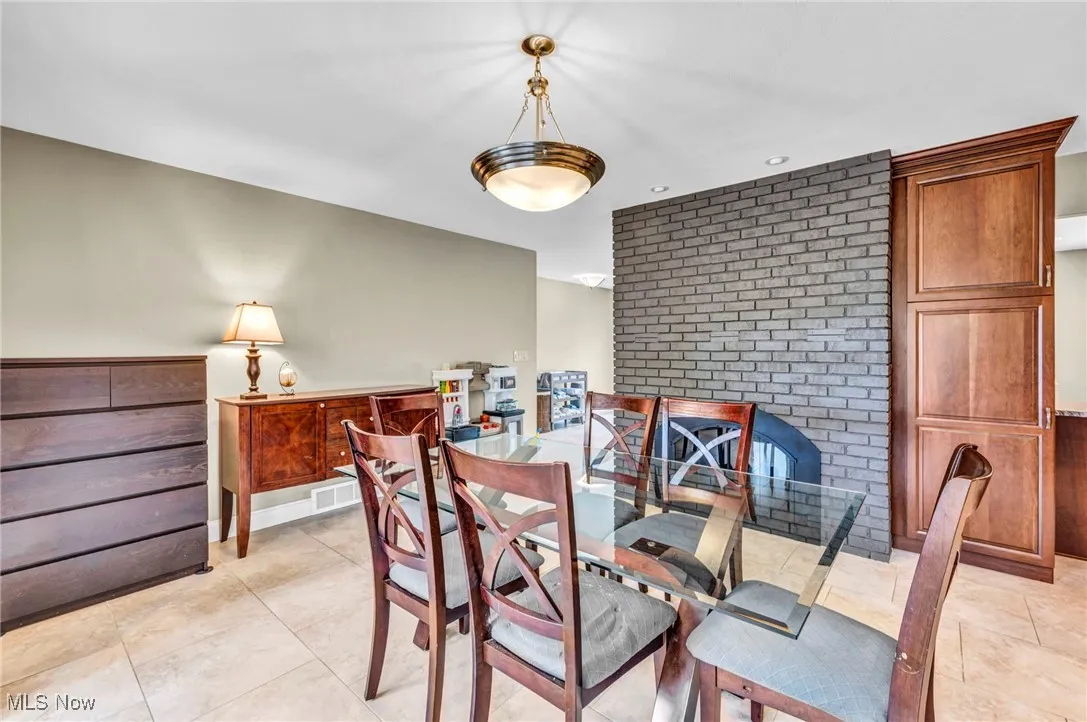 Dining area with light tile patterned flooring, brick wall, and recessed lighting