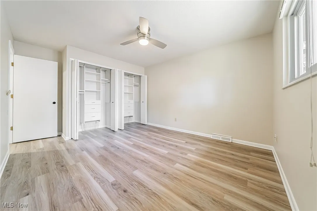 Unfurnished bedroom featuring multiple closets, light wood finished floors, and ceiling fan