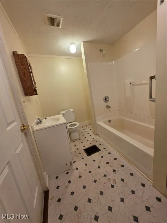 Full bathroom featuring a textured ceiling, shower / washtub combination, vanity, ornamental molding, and light tile patterned flooring unit 1