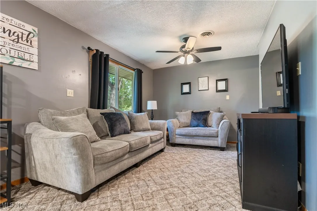Living room with a textured ceiling and ceiling fan