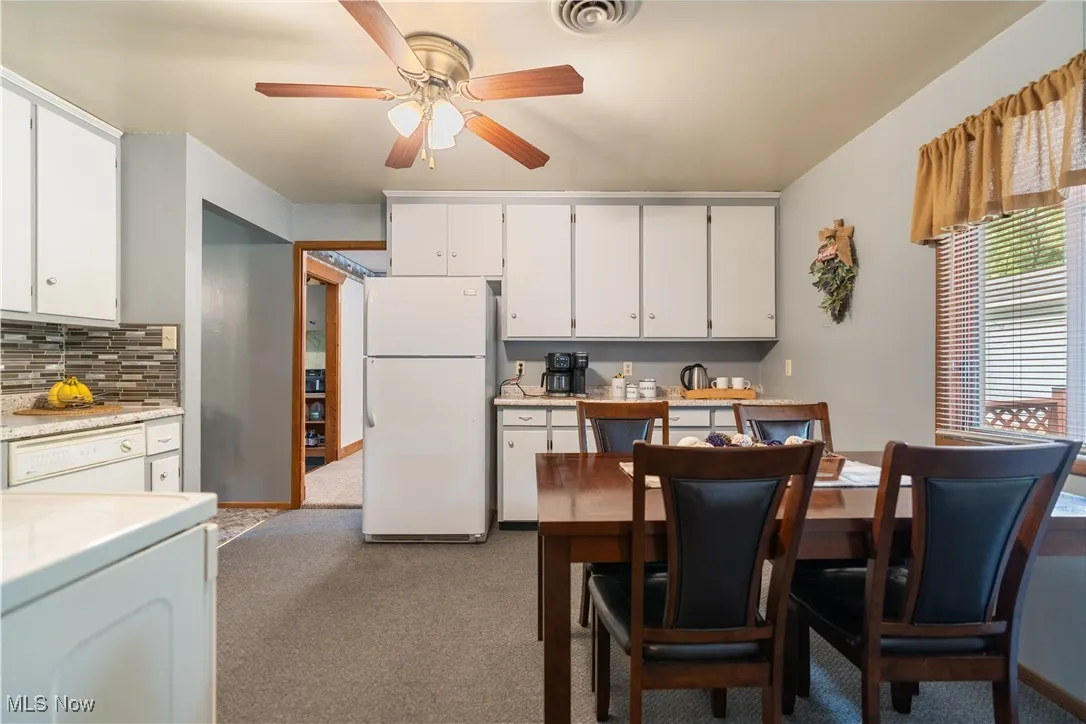 Kitchen featuring white appliances, white cabinetry, light colored carpet, and washer / clothes dryer