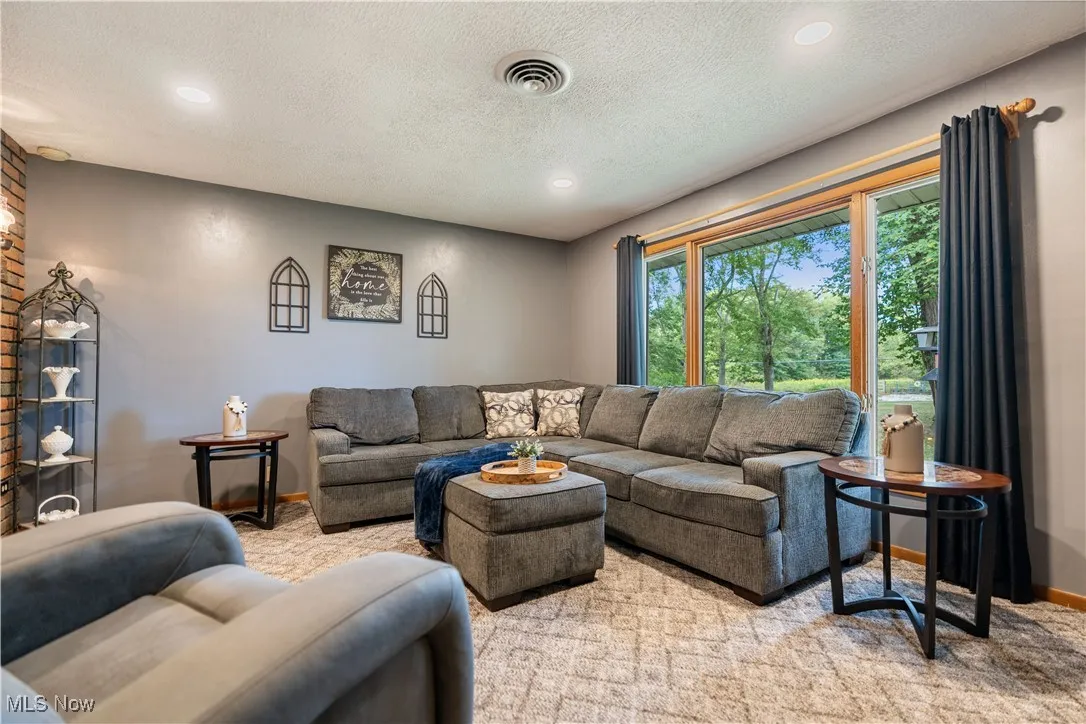 Carpeted living room featuring a textured ceiling and recessed lighting