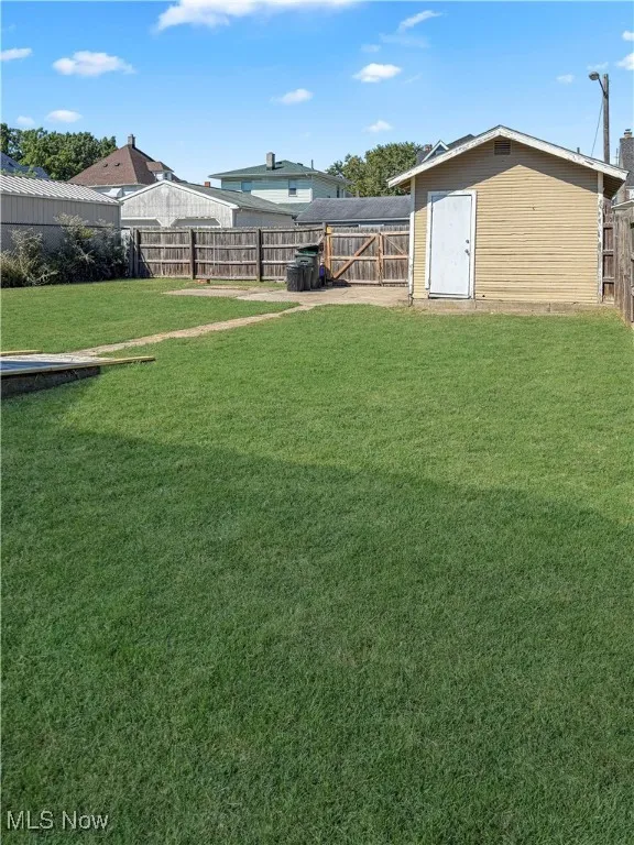 Fenced backyard featuring an outbuilding