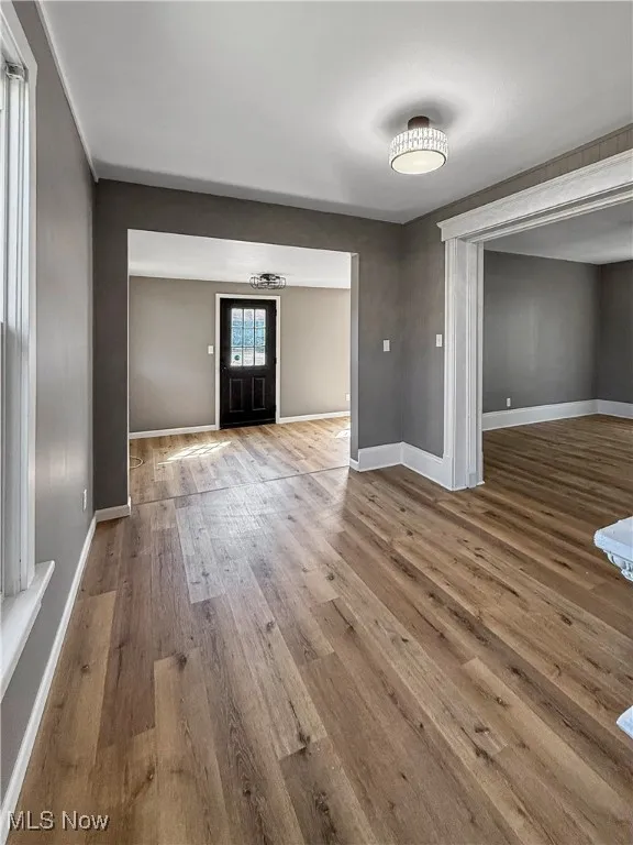 Unfurnished living room featuring baseboards and light wood finished floors