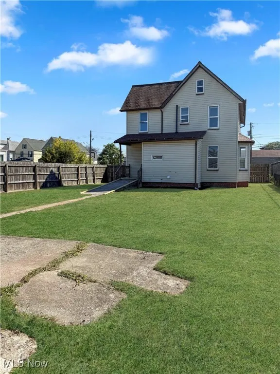 Rear view of house with a fenced backyard and a shingled roof