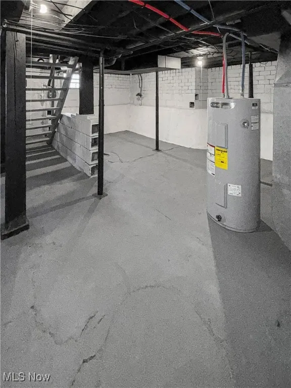 Unfinished basement with electric water heater and stairs