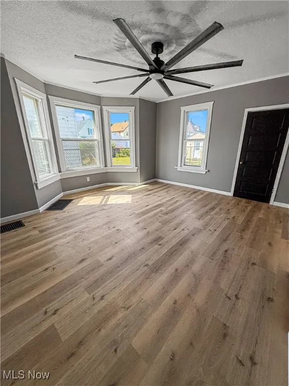 Unfurnished bedroom with a textured ceiling, light wood-type flooring, and ceiling fan