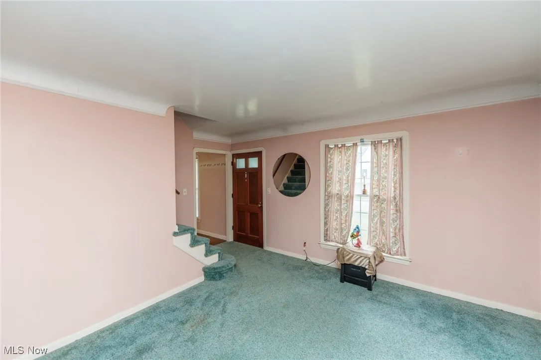 Foyer entrance with carpet flooring, crown molding, and stairs